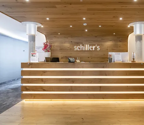 Moderne Rezeption im Tagungshotel schiller‘s in Olching mit viel Holz und indirekter Beleuchtung