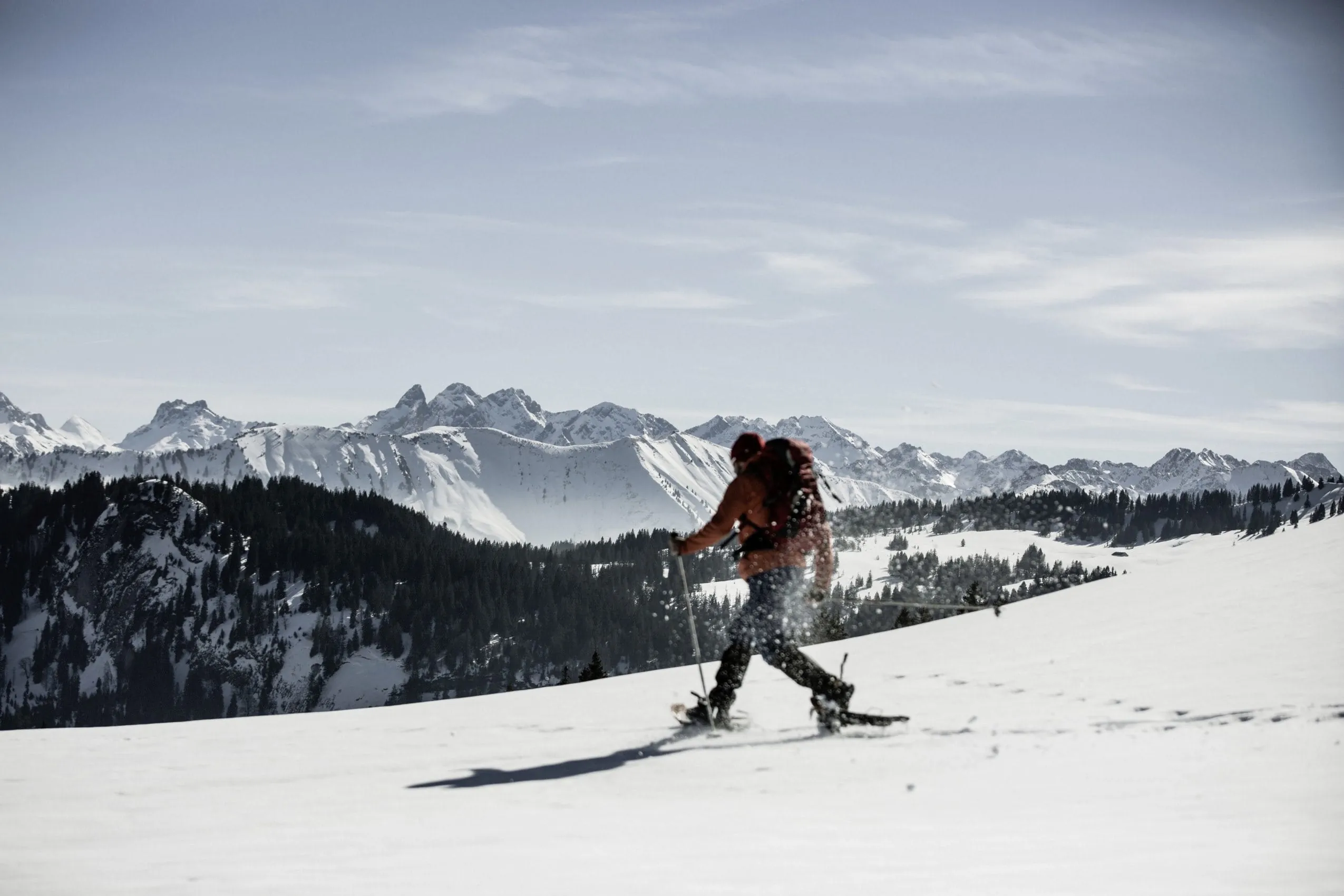 Person beim Schneeschuhwandern in der verschneiten Bergregion rund um das HUBERTUS Mountain Refugio Allg&auml;u