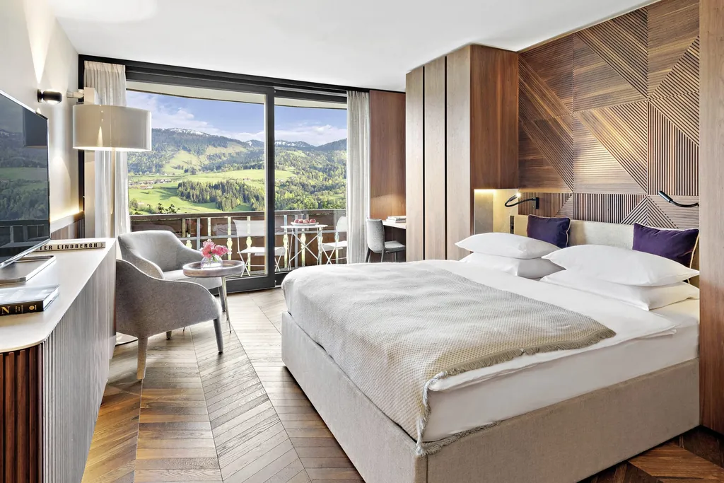 Doppelzimmer im Hotel Allgäu Sonne mit Holzvertäfelung am Bettkopf und Blick über den Balkon in die Berge