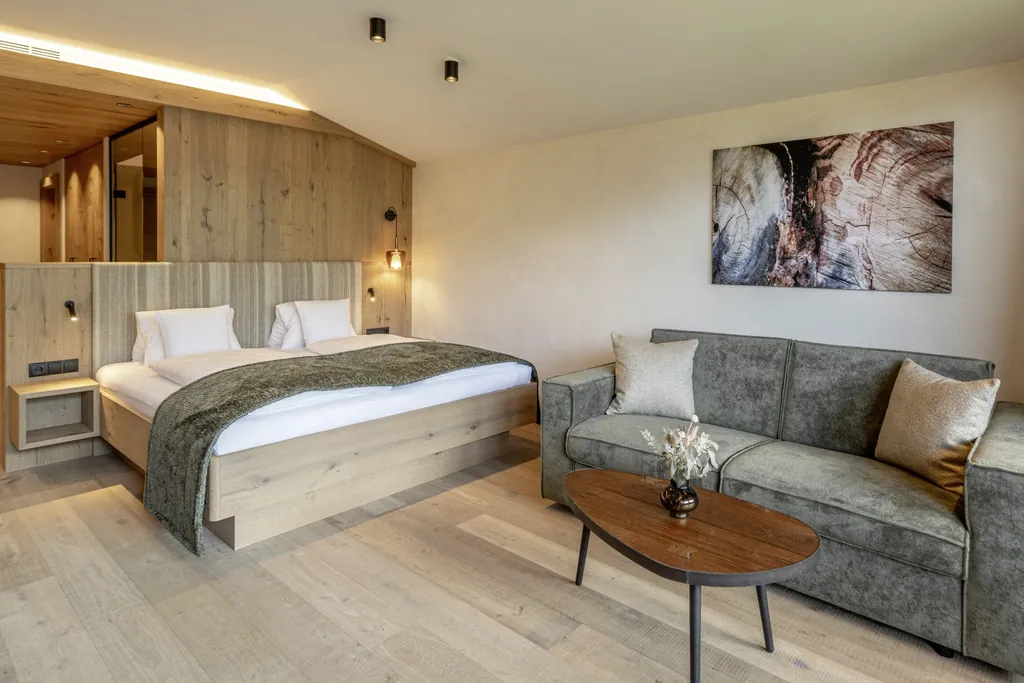 Doppelzimmer mit grauem Sofa und moderner Kunst an der Wand im Alpbacherhof