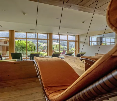 orange Hängeliege im Ruheraum des Alpbacherhof mit Blick in den Garten