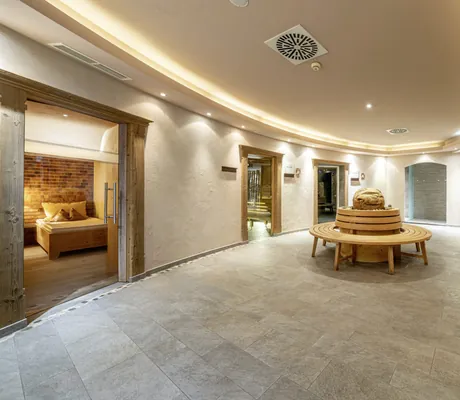 Spabereich im Alpbacherhof mit runder Holzbank und Zugängen zu den Saunen
