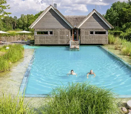 Mann und Frau schwimmen im türkisen Wasser des Outdoorpool des BEECH Resort Plauer See