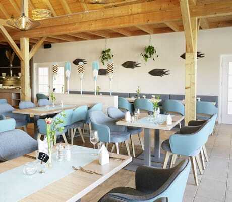 Restaurant im BEECH Resort Plauer See mit türkisen Sesseln und angemalten Rudern als Dekoration