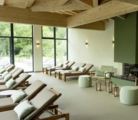 Ruheraum im BEECH Resort Plauer See mit dicken Holzbalken und grünem Kamin