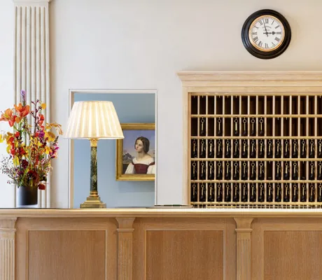 Rezeption in Brenners Park-Hotel & Spa mit traditionellem Schlüsselregal und alter Wanduhr