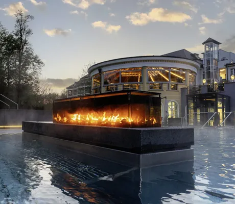 Feuerstelle im Infinity-Außenpool des Hotel Der Sonnenhof in der Dämmerung