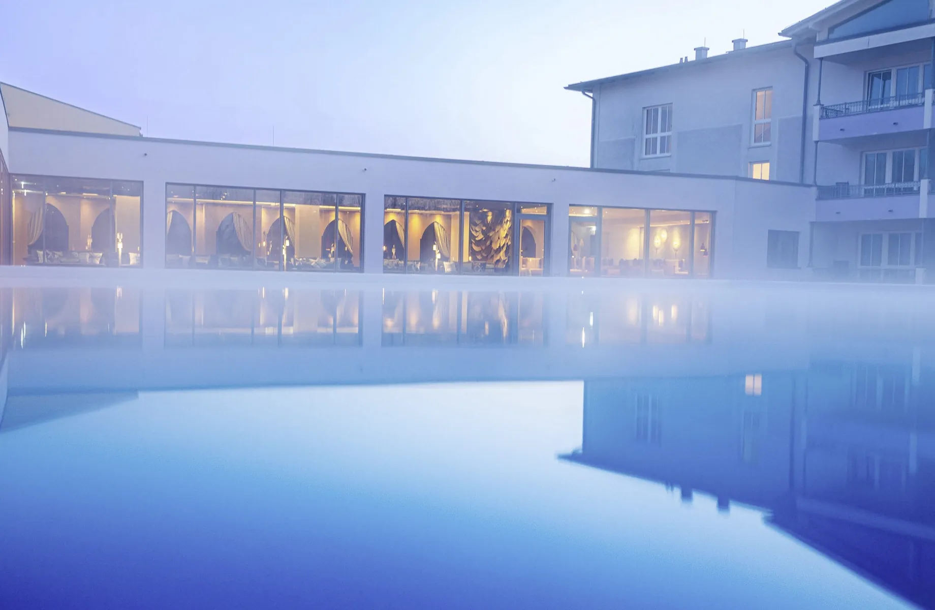 Outdoorpool im Hotel Holzapfel im Morgennebel mit Blick in die Ruheräume
