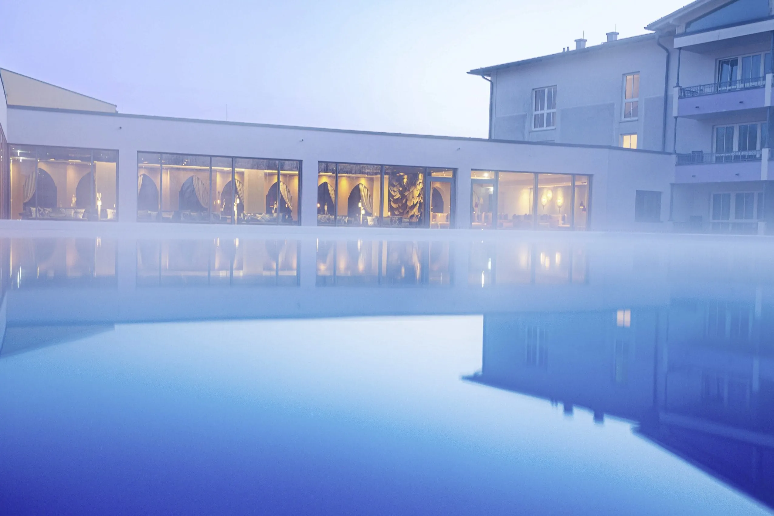 Outdoorpool im Hotel Holzapfel im Morgennebel mit Blick in die Ruheräume