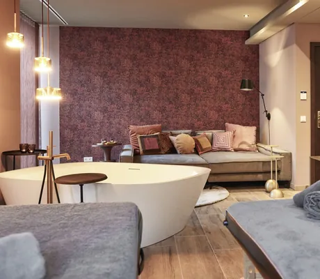 Private Spa im Hotel Holzapfel mit großer freistehender Doppelbadewanne und weinroter Blumentapete