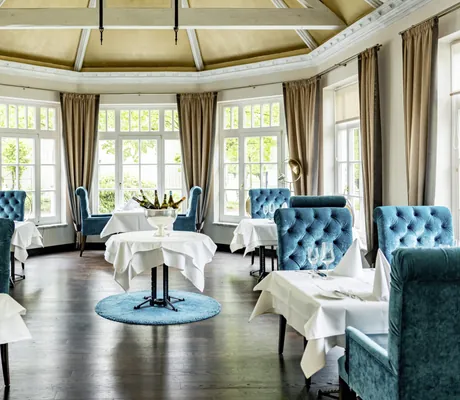 Restaurant im Hotel Holzapfel mit blauen Samtstühlen und Sektkühler in der Mitte