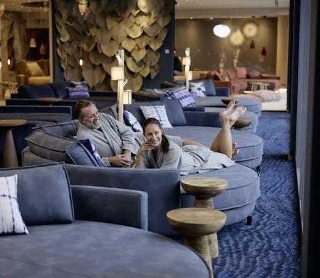 Paar liegt auf großen runden Ruheliegen im blauen Ruheraum des Hotel Holzapfel
