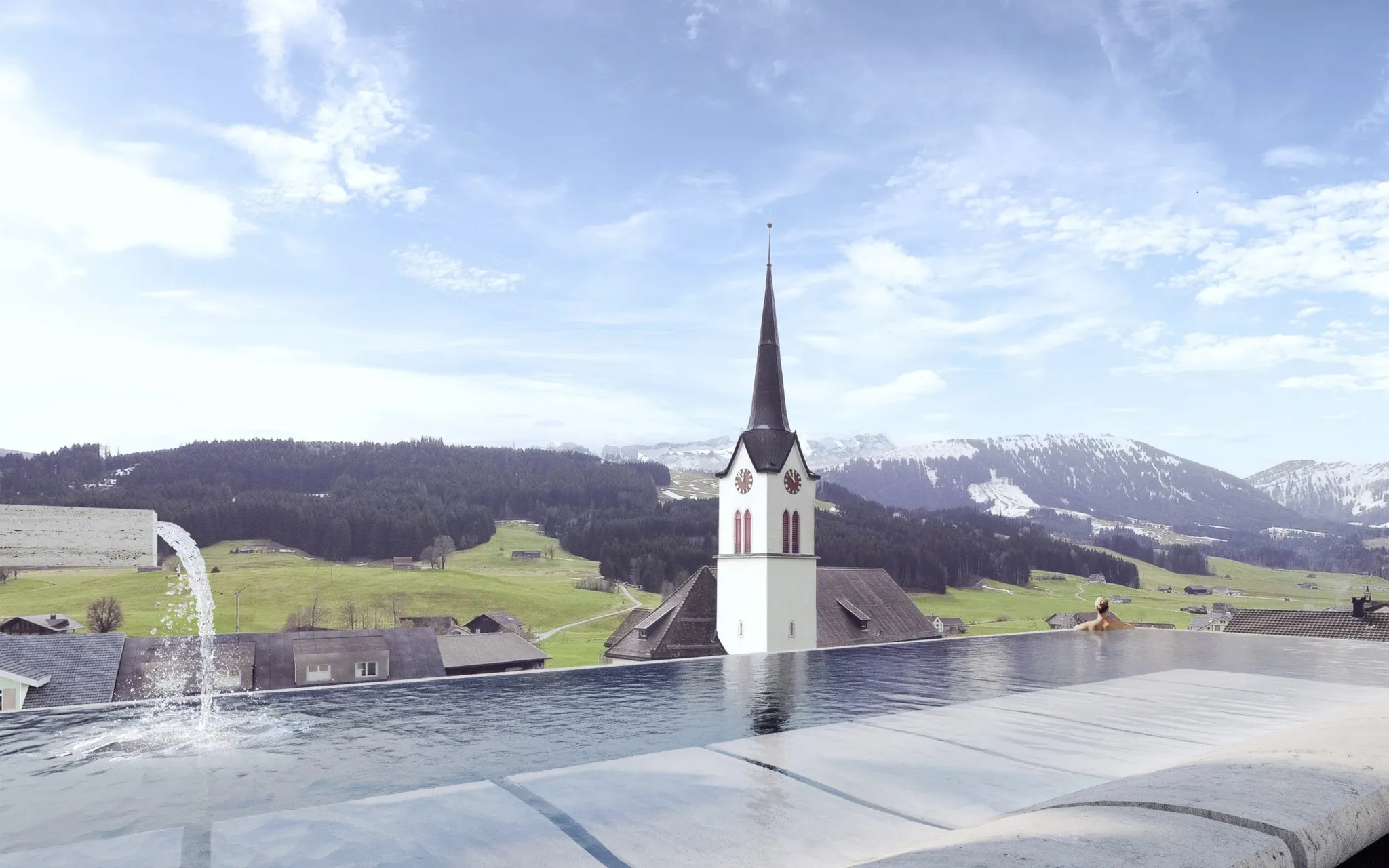 Infinitypool auf dem dach des Huus Quell mit Blick auf den Kirchturm und die Berge