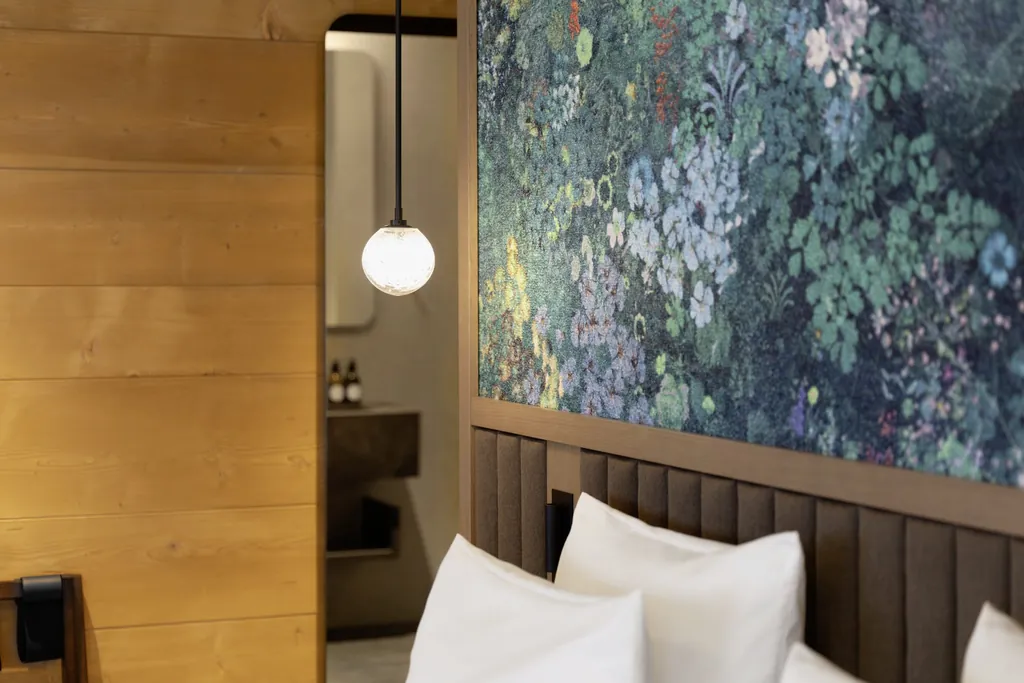 Detail am Bett im Huus Quell mit Blumentapete hinter dem Bett