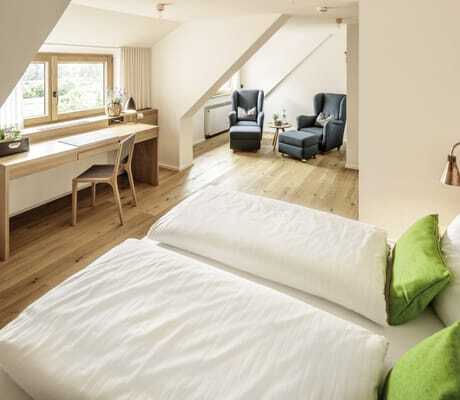 Doppelzimmer in der Kuroase im Kloster mit Ohrensesseln in einer Ecke und grünen Kissen auf dem Bett