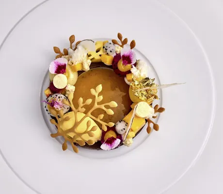 Gourmetgericht mit verschiedenen Desserarten udn Blüten auf weißem Teller im Landromantikhotel Oswald