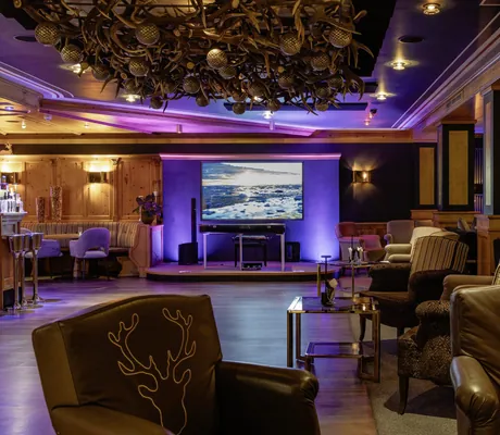 Lobby im Landromantikhotel Oswald mit Hirschgeweihen an der Decke und großem Screen