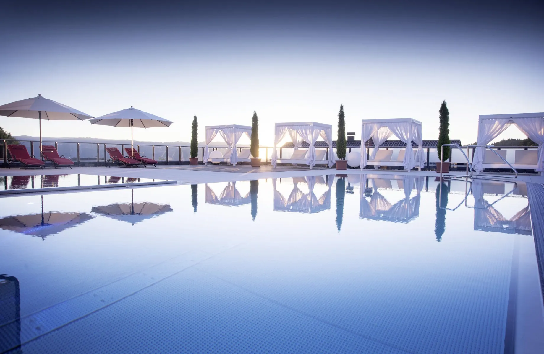 Outdoorpool im Landromantikhotel Oswald mit weißen Daybeds am Rand