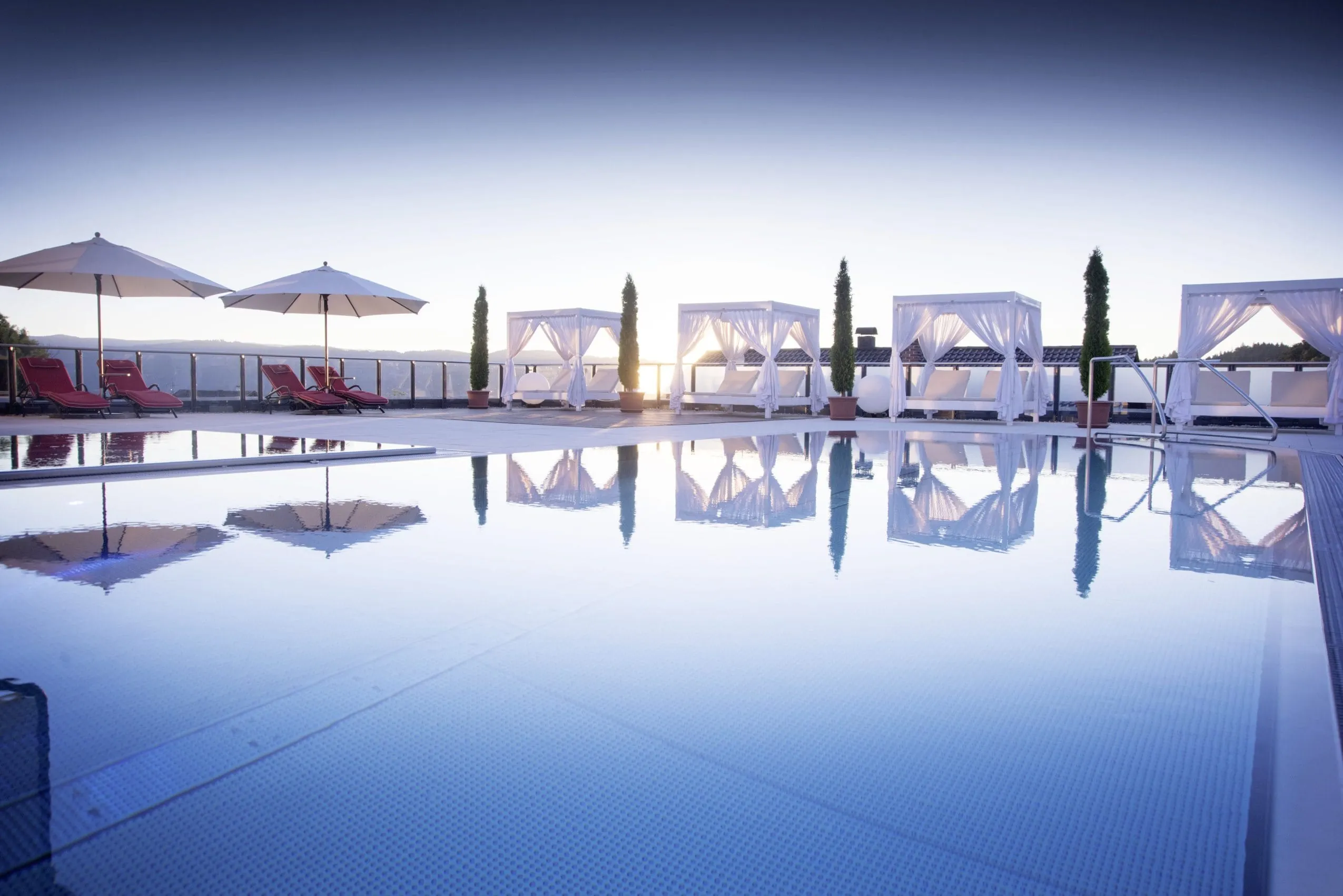 Outdoorpool im Landromantikhotel Oswald mit weißen Daybeds am Rand