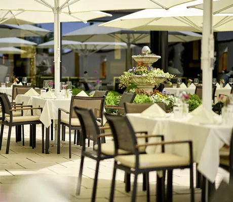 Terrasse im Landromantikhotel Oswald mit blumengeschmücktem Brunnen und gedeckten Tischen