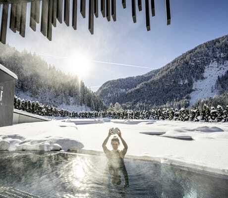 Frau hält Herz aus Stein im Lürzerhof-Pool in die Höhe im Winter