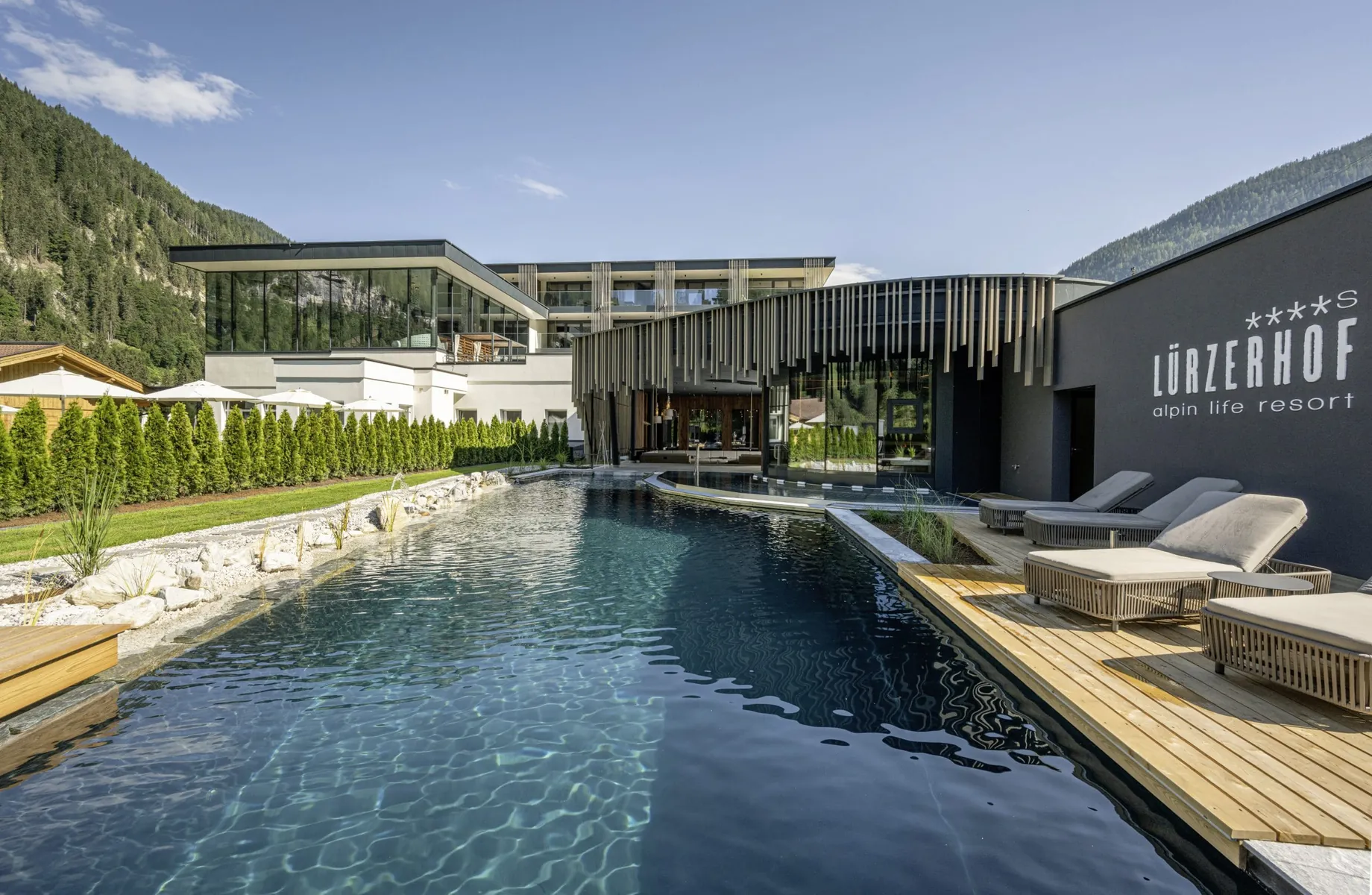Outdoorpool im Lürzerhof mit Blick auf das große Spafenster mit hängenden Röhren