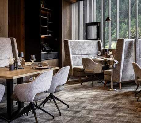 Restaurant im Lürzerhof mit grauen Polstersesseln an gedeckten Holztischen