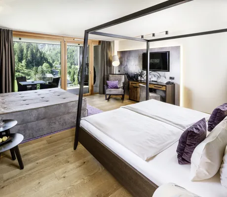 Zimmer im Lürzerhof mit schwarzem Himmelbett und grauem Doppelsofa