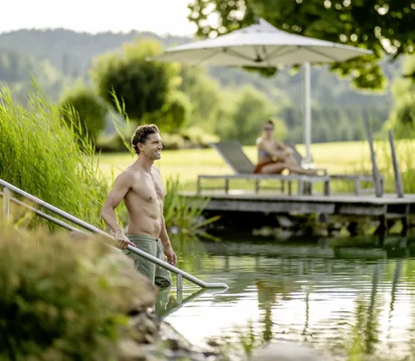 Mann geht über die Treppe in den Naturbadeteich des Mooshof