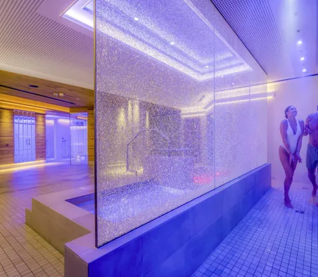 Paar mit Badebekleidung geht in die Erlebnisduschen neben dem Kneippbecken im Mooshof