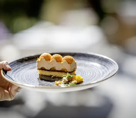 Dessert mit orangen Kugeln als Topping auf blauem Teller im Mooshof