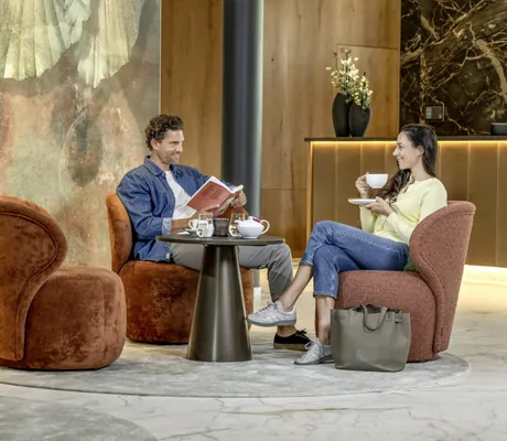 Paar sitzt auf terrakottafarbenen Sesseln in der Lobby beim Kaffee im Mooshof