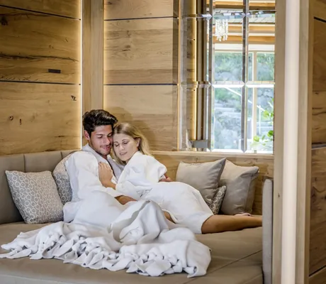 Paar liegt in Bademänteln in einer Kuschelecke im Mooshof