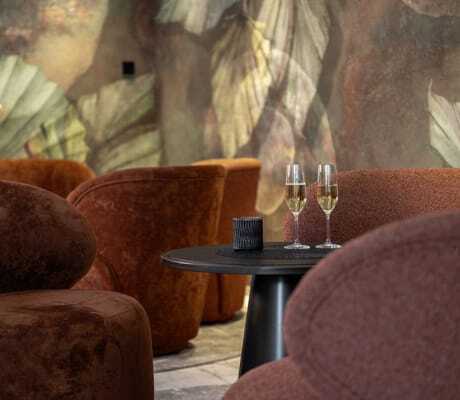terrakottafarbene Sessel an einem schwarzem Tisch mit zwei Gläsern Prosecco im Mooshof