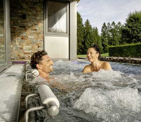 Paar liegt lachend im Whirlpool des Mooshof