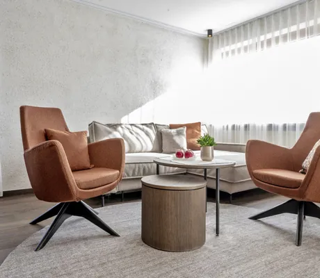 terrakottafarbene Sessel an einem grauen Sofa im Zimmer des Mooshof