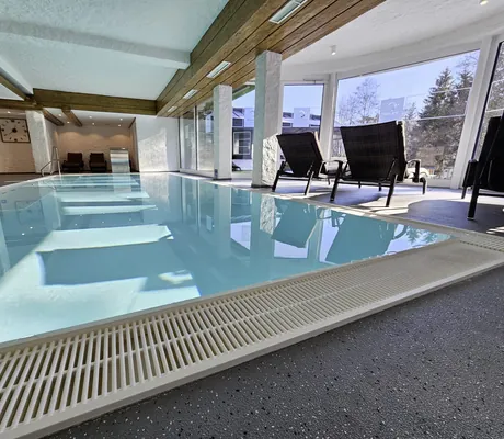 Indoorpool im Naturhotel Waldesruhe mit Blick auf eine große Uhr