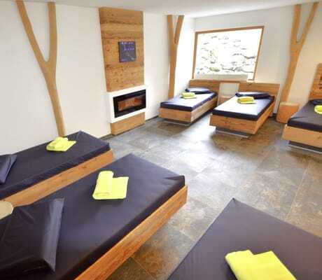 Ruheraum im Naturhotel Waldesruhe mit schwarzen Liegen und gelben Handtüchern