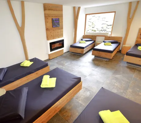 Ruheraum im Naturhotel Waldesruhe mit schwarzen Liegen und gelben Handtüchern