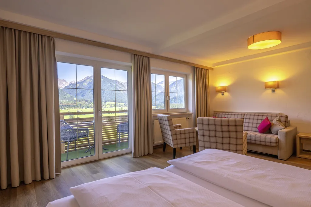 Zimmer im Naturhotel Waldesruhe mit karierten Sitzmöbeln und Blick auf die Berge