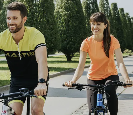 Paar in gelbem und orangem Shirt radelt die Alle am Ortner's Resort entlang