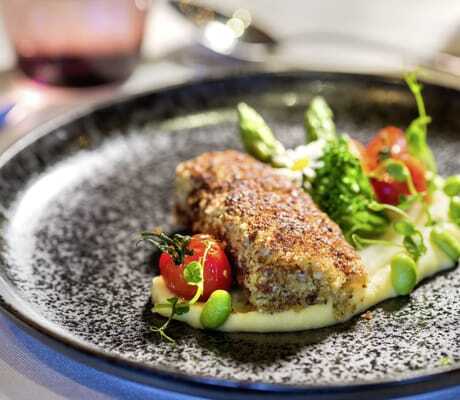 Fischgericht mit Tomaten und Edamame auf schwarzem Teller im Ortner's Resort