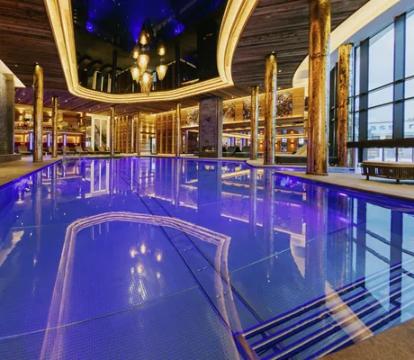 Indoorpool im Ortner's Resort mit goldenen Säulen bei Nacht