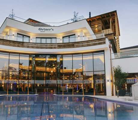 Panoramafenster vom Outdoorpool mit Blick in den Wellnessbereich des Ortner's Resort am Abend