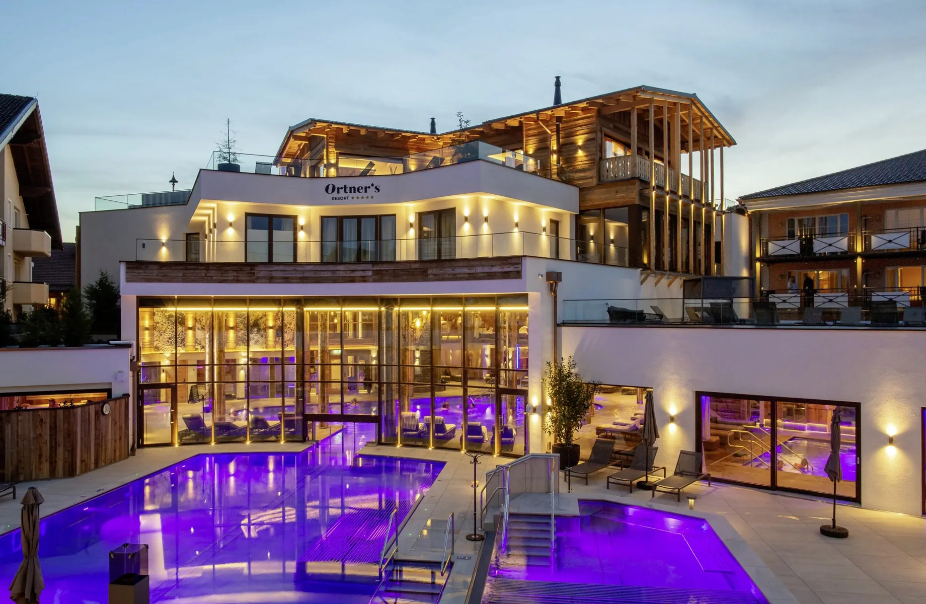 Blick auf beleuchteten Outdoorpool und Fassade des Ortner's Resort bei Nacht