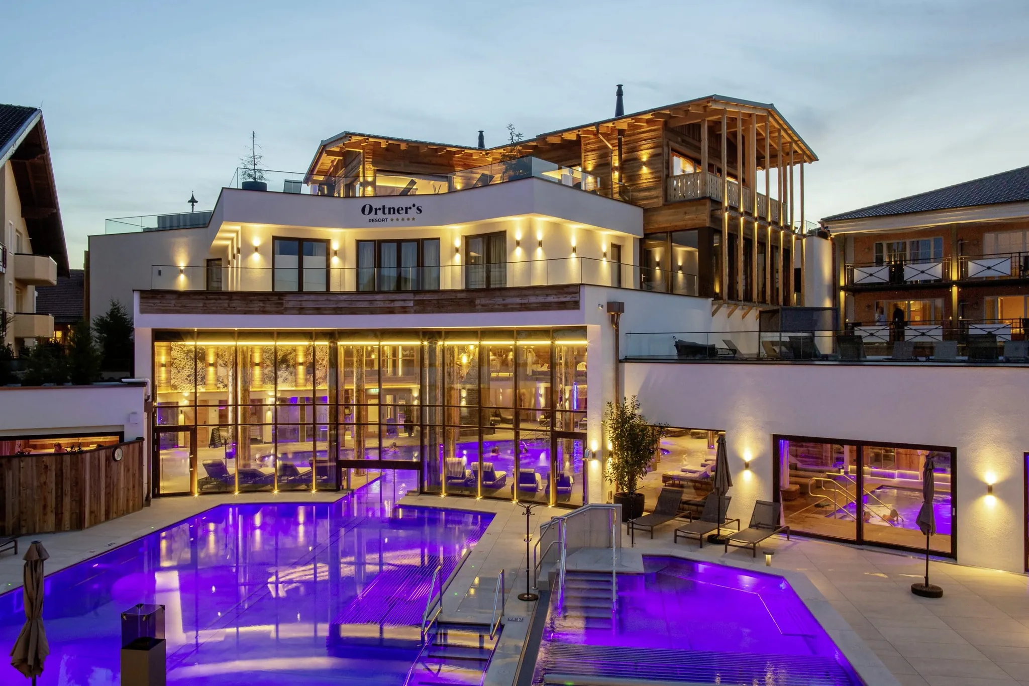 Blick auf beleuchteten Outdoorpool und Fassade des Ortner's Resort bei Nacht