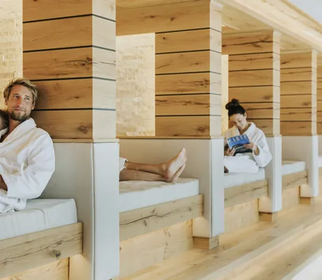 Paar in weißem Bademantel kuschelt in Ruhekoje mit hellen Polstern im Ortner's Resort