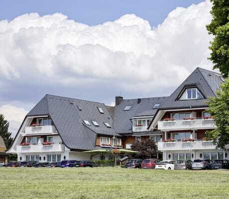 Fassade des Hotel Reppert mit weißen Balkonen und parkenden Autos davor