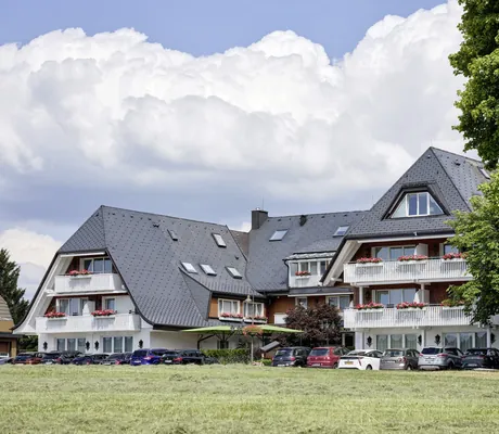 Fassade des Hotel Reppert mit weißen Balkonen und parkenden Autos davor