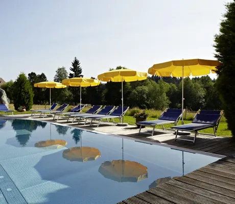 Outdoorpool mit blauen Liegen und gelben Sonnenschirmen im Hotel Reppert